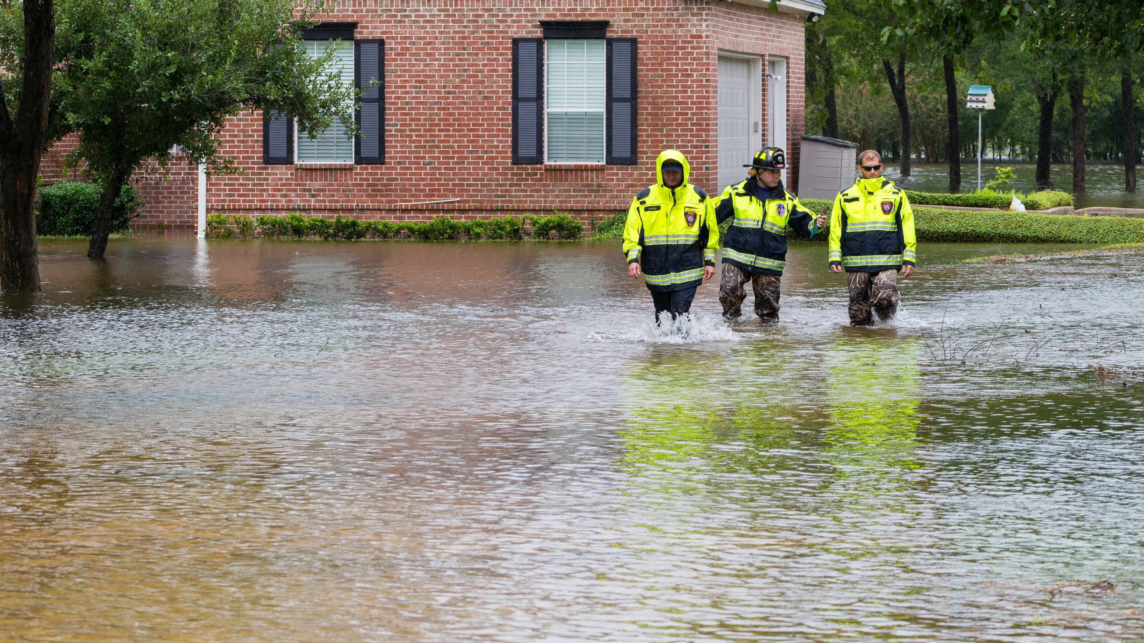 emergency workers walking through flood waters after the storm