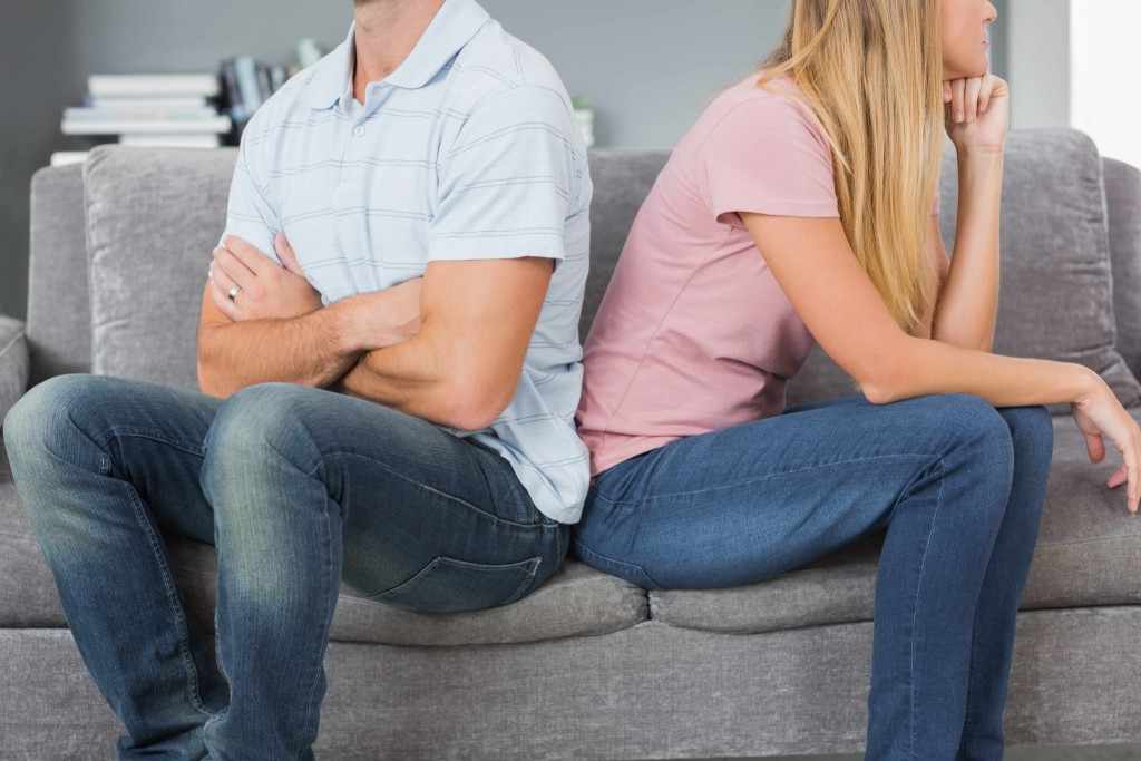 a man and woman sitting back to back after argument, hurting each other
