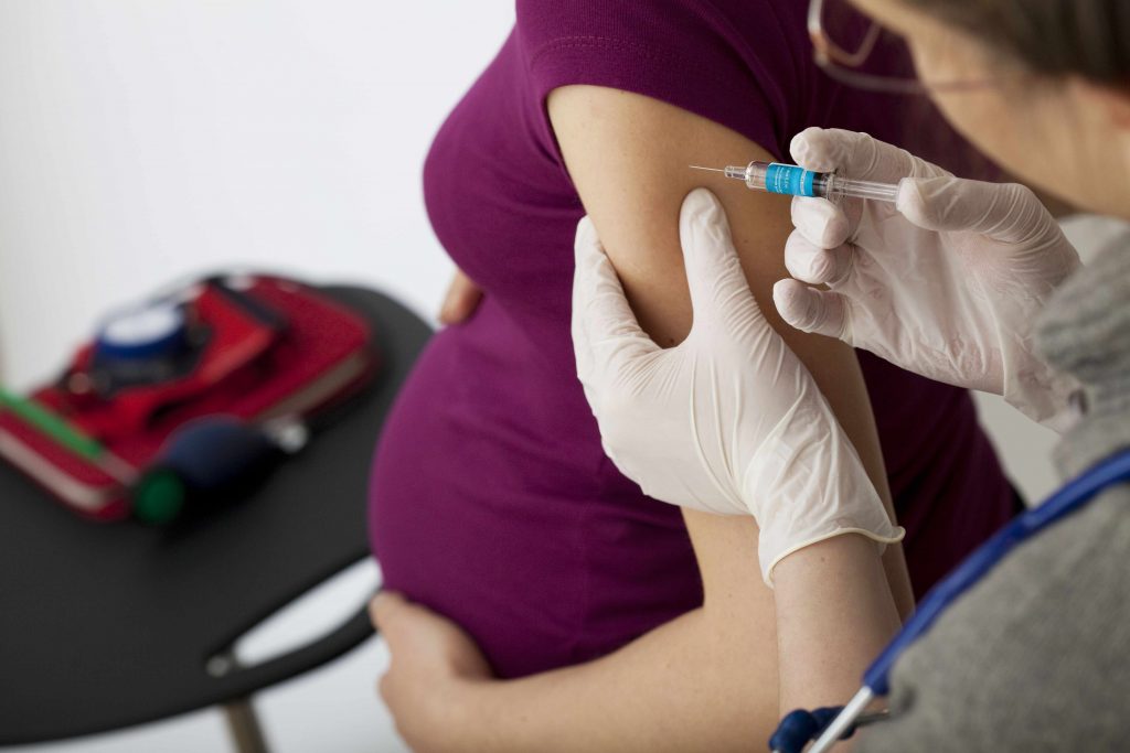 a young pregnant woman receiving a vaccination in her upper arm