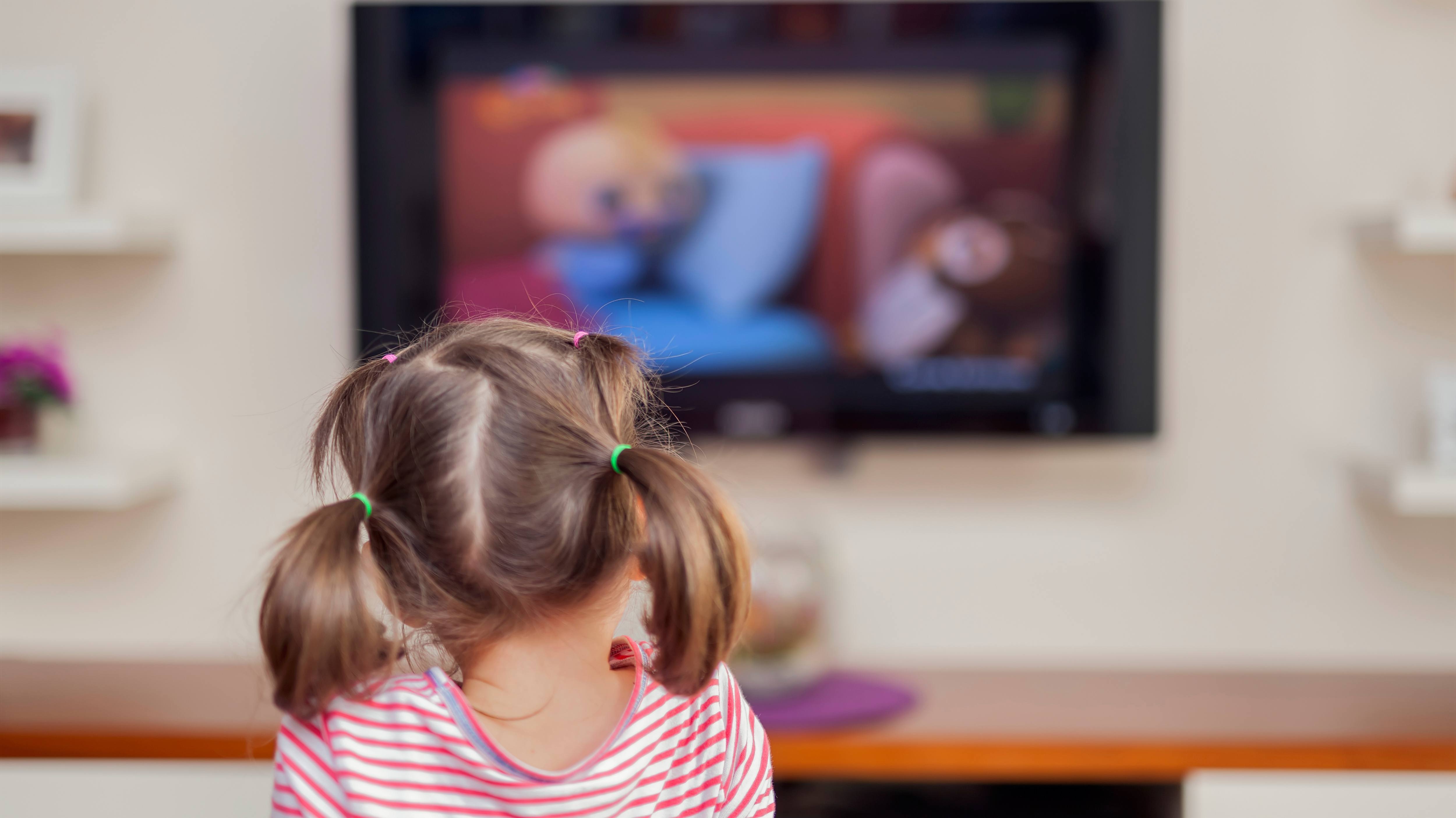 a little girl sitting in front of a TV screen