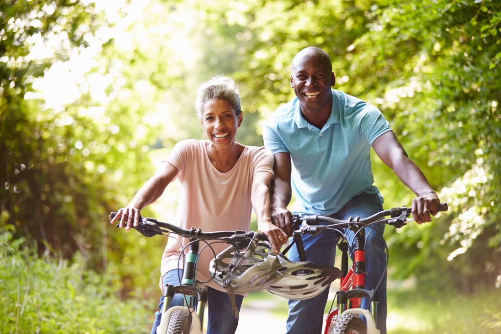 a smiling middle-aged couple on bicycles