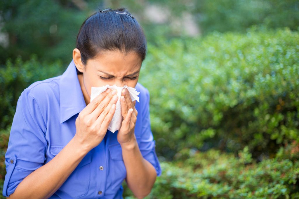 a woman blowing her nose into a tissue, sneezing