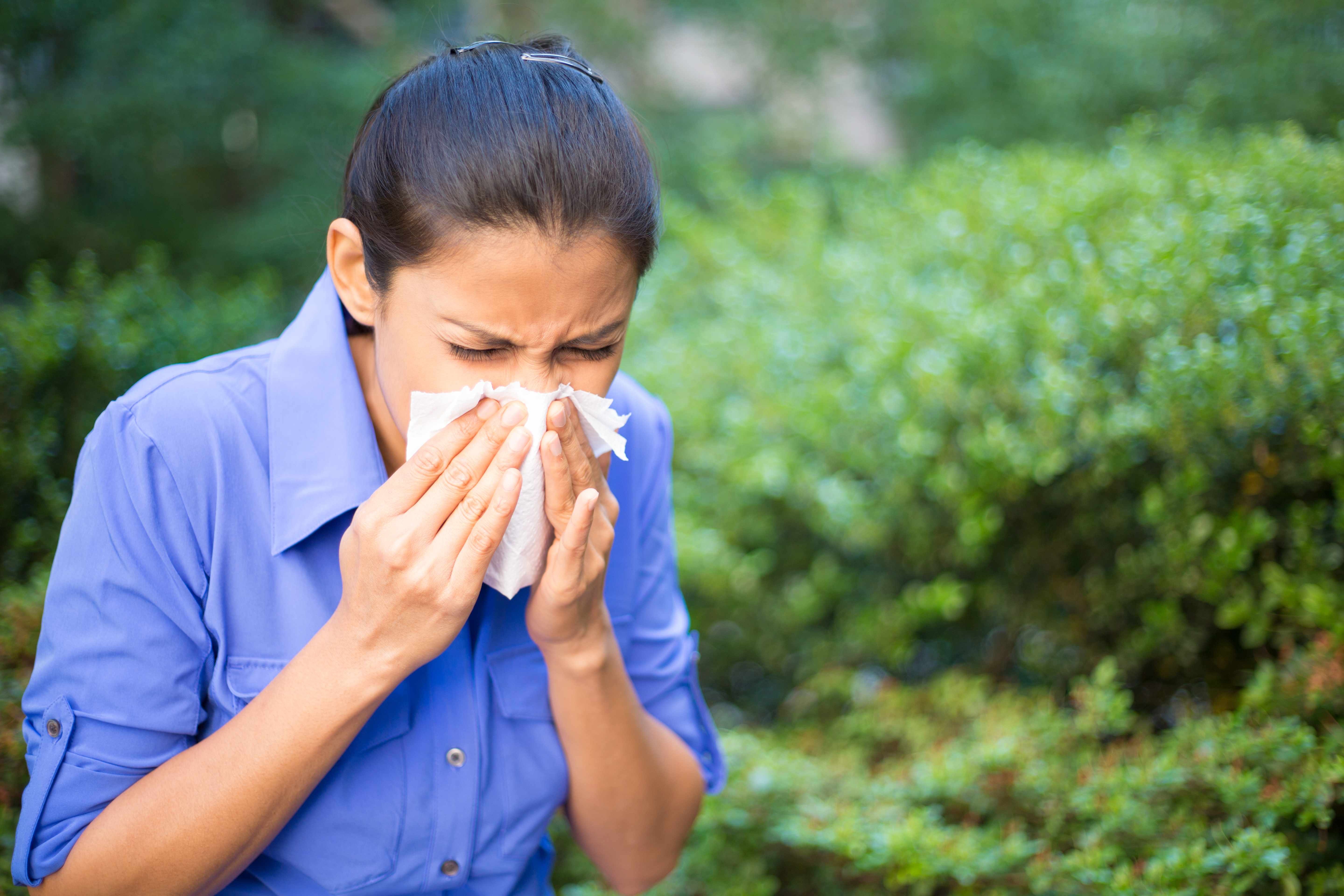 a woman blowing her nose into a tissue, sneezing