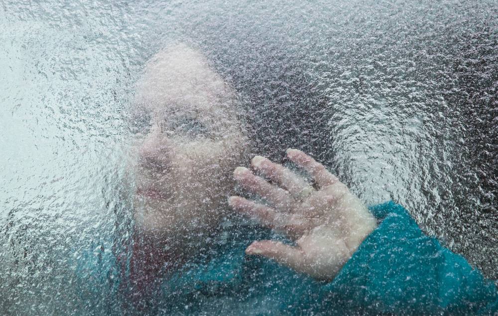 woman looking through window covered in ice