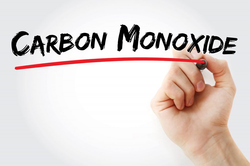 a hand holding a marker and writing the words carbon monoxide