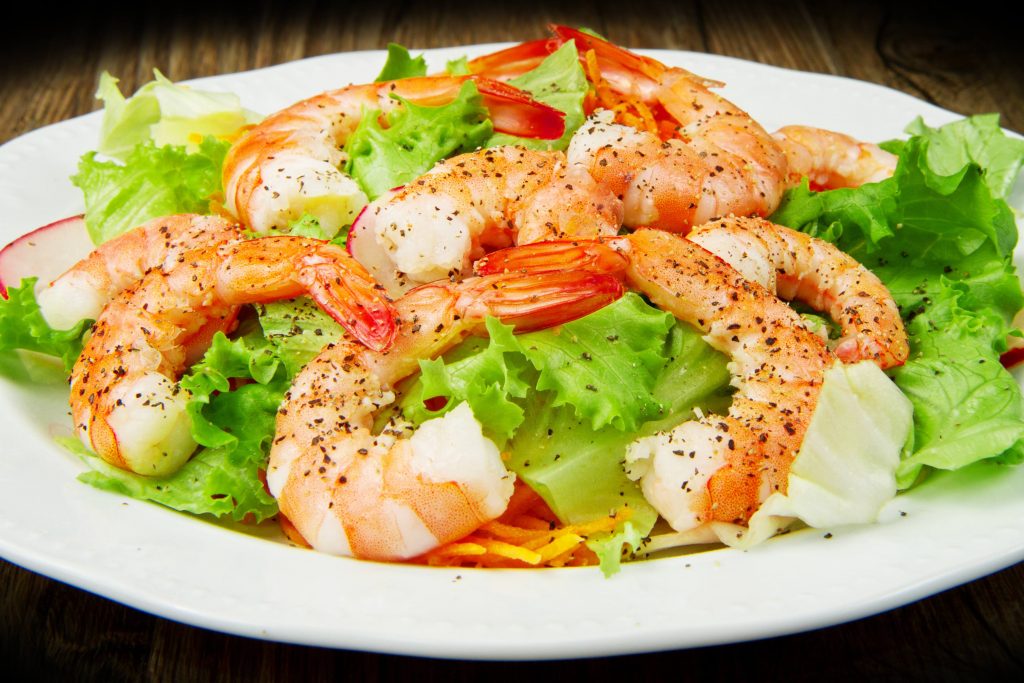 a close-up of a plate of shrimp and mixed greens