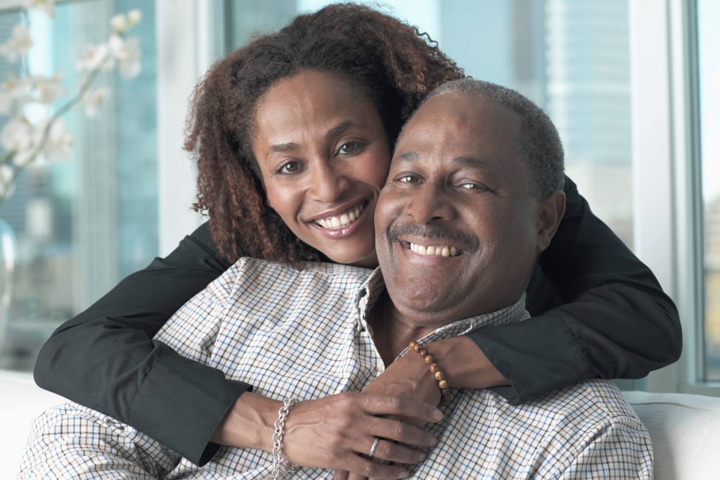 a middle-aged African American couple smiling and hugging