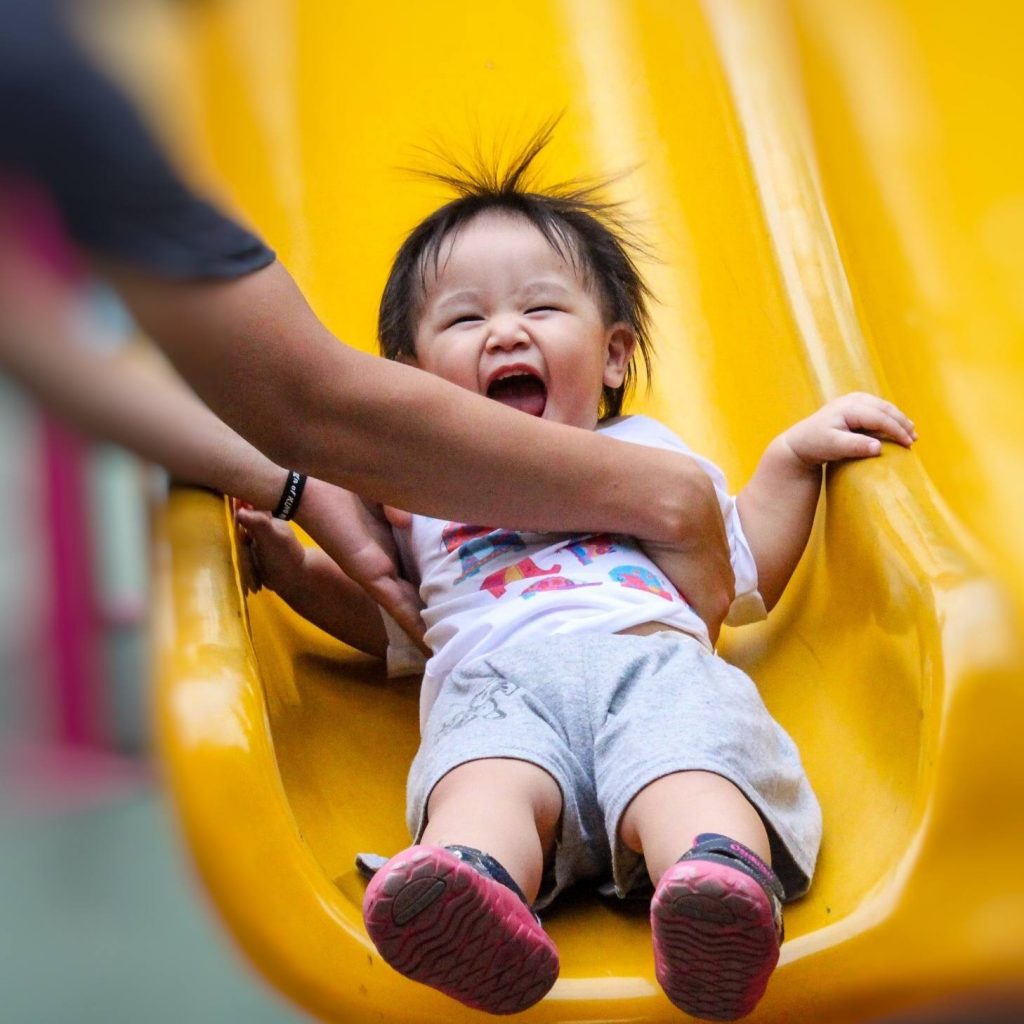 a small boy sliding down a playground slide