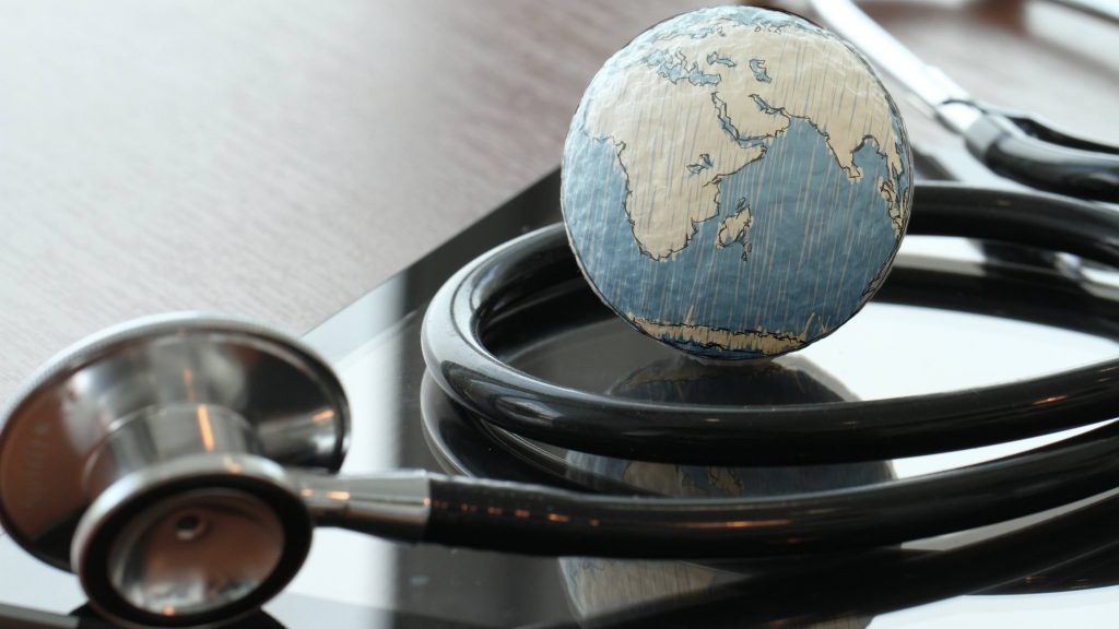 a stethoscope with a small globe resting on the table, too, representing world health