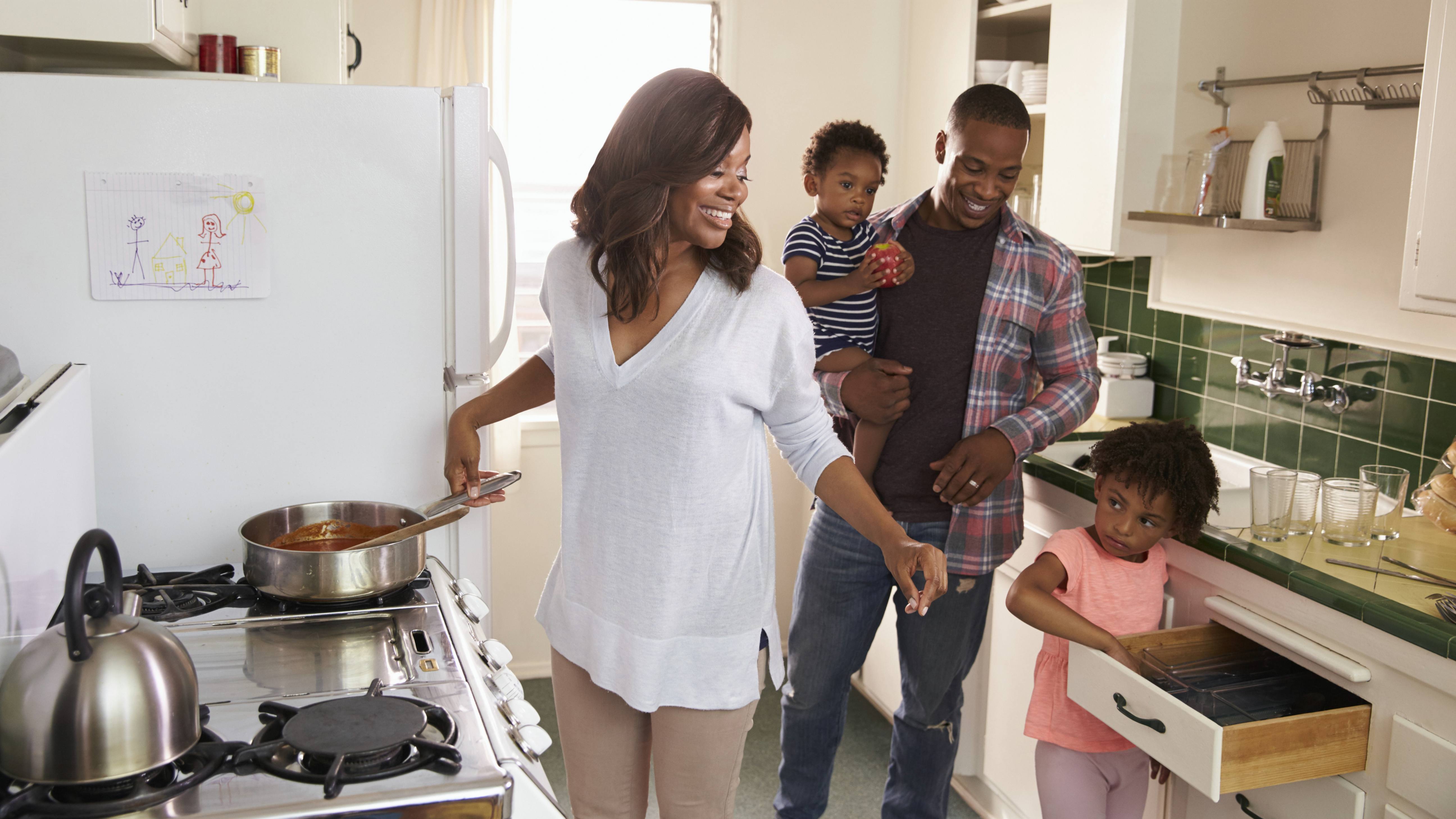 an African-American couple with children in the kitchen and cooking together