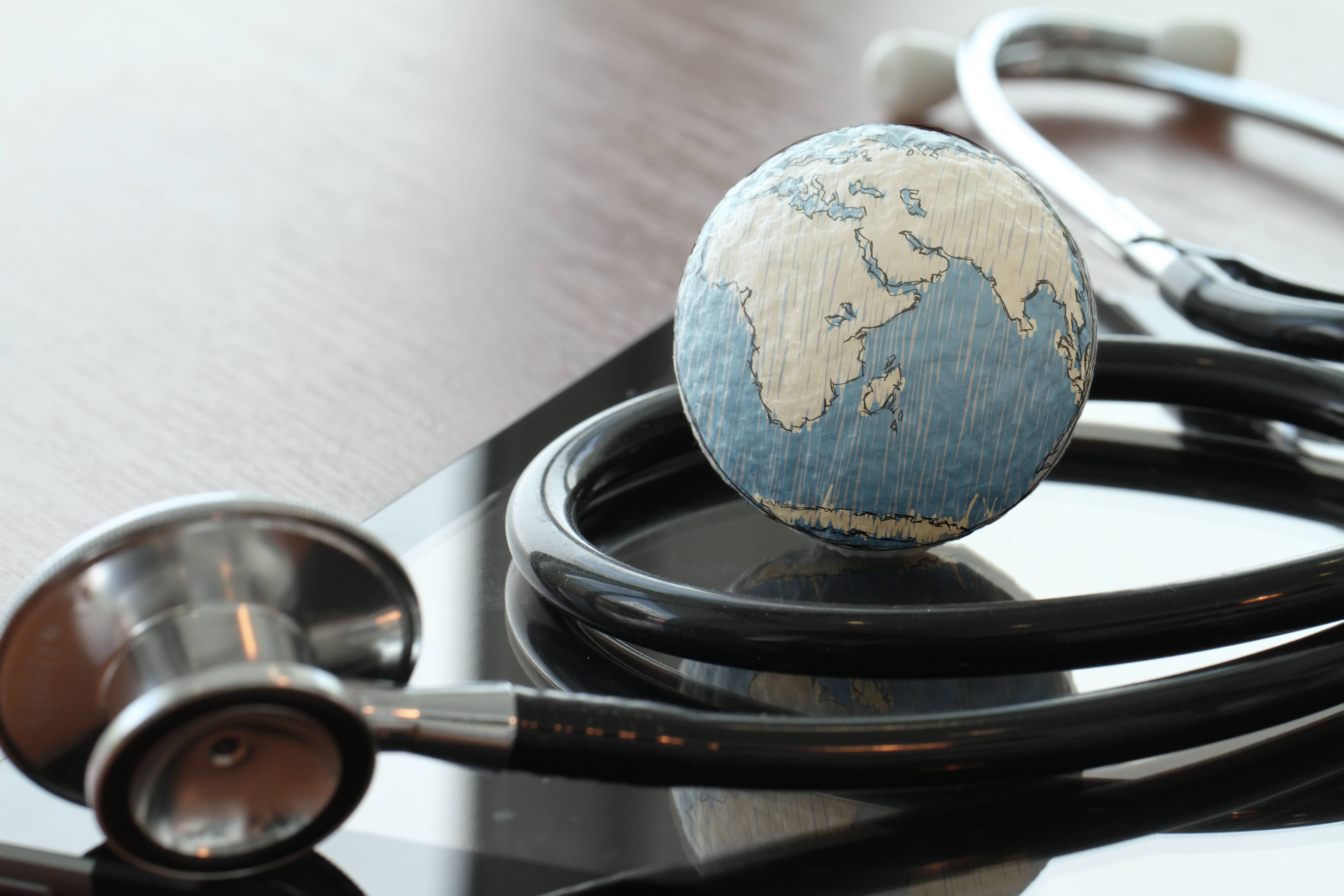 a stethoscope with a small globe resting on the table, too, representing world health