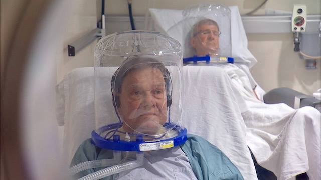 two patients in clear hyperbaric helmets on in the hyperbaric chamber
