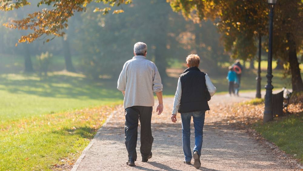 Una pareja de ancianos pasea por el parque una mañana de otoño