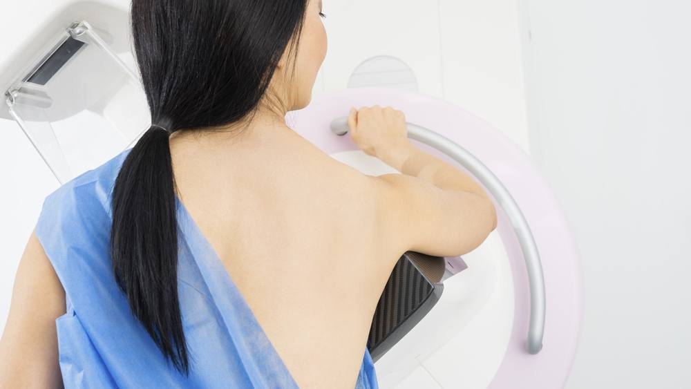 Mujer de pie frente a la máquina de mamografía