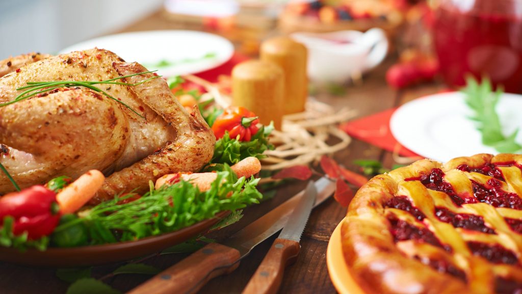 a festive holiday table with turkey, fresh vegetables and pie
