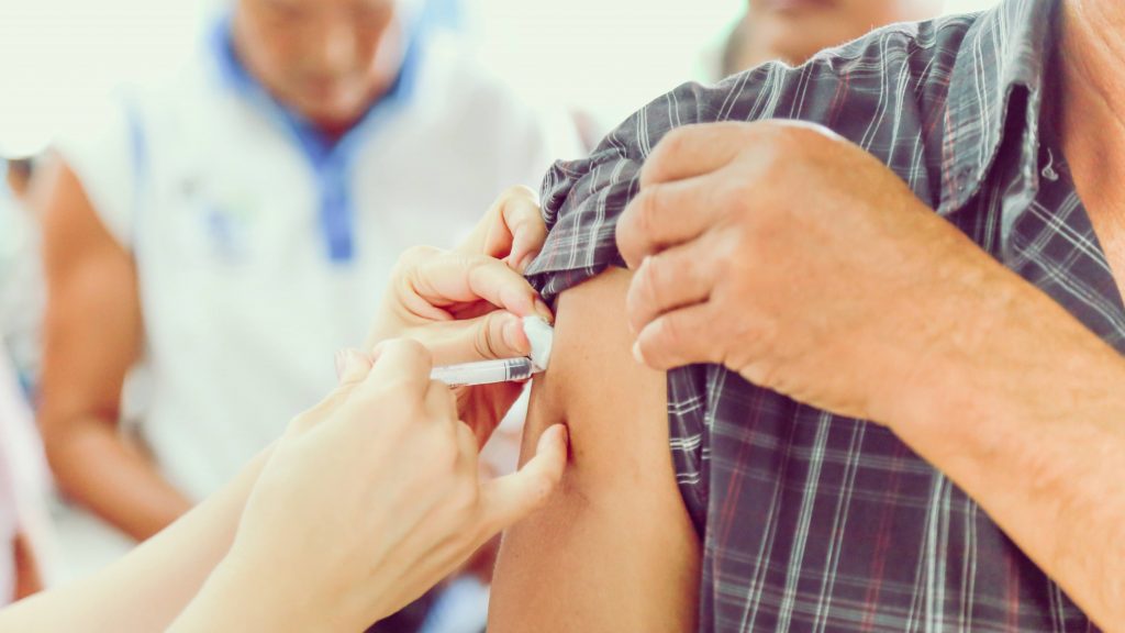 a person getting vaccinated by a healthcare person giving a flu shot