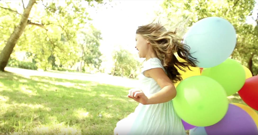 girl running with balloons outdoors