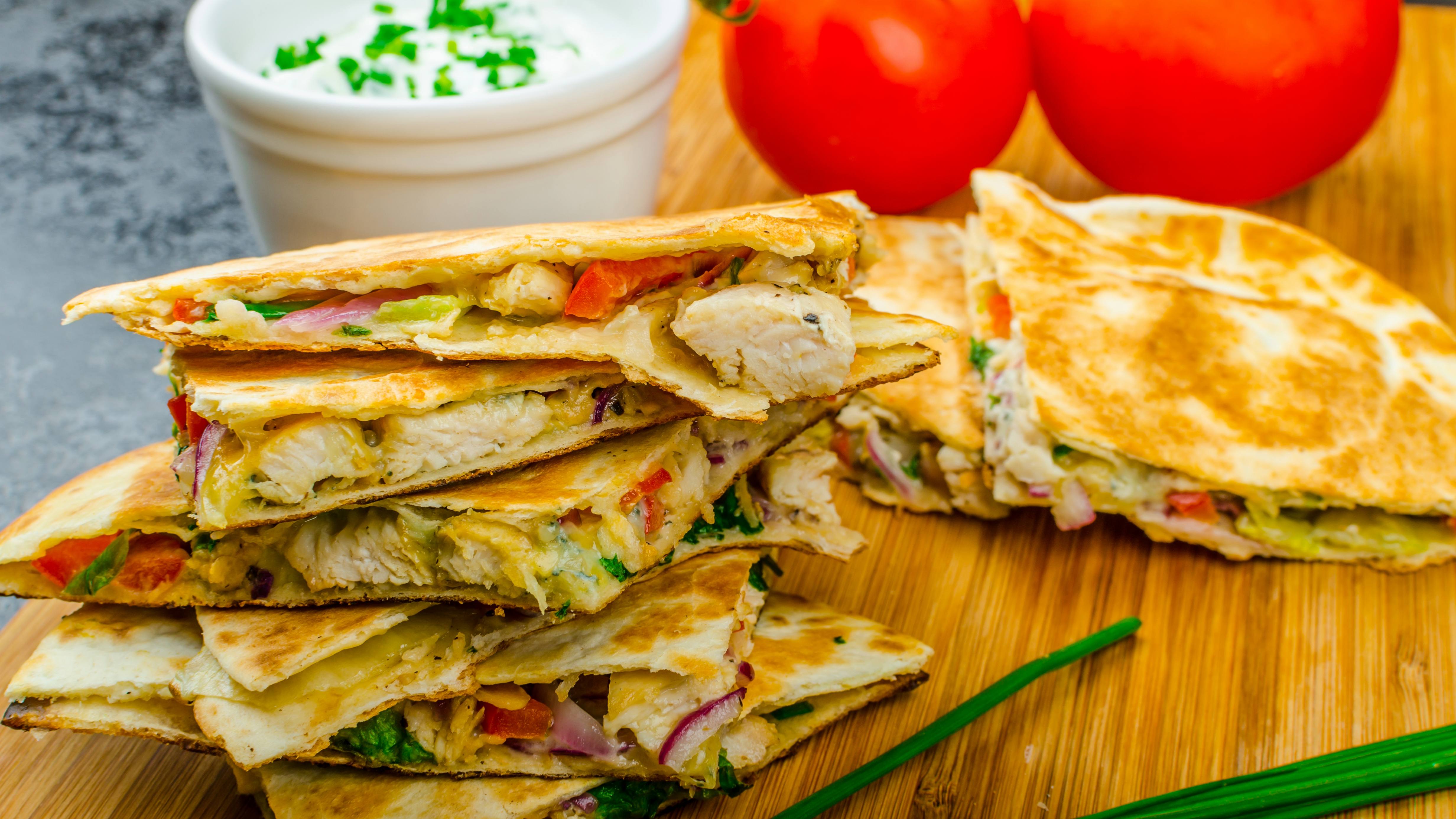 a chicken and vegetable quesadilla on a wooden plank
