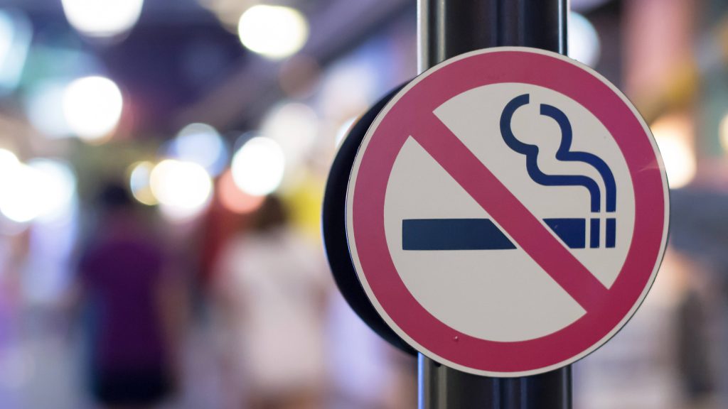 Acercamiento de una señal de no fumar colocada en una concurrida calle