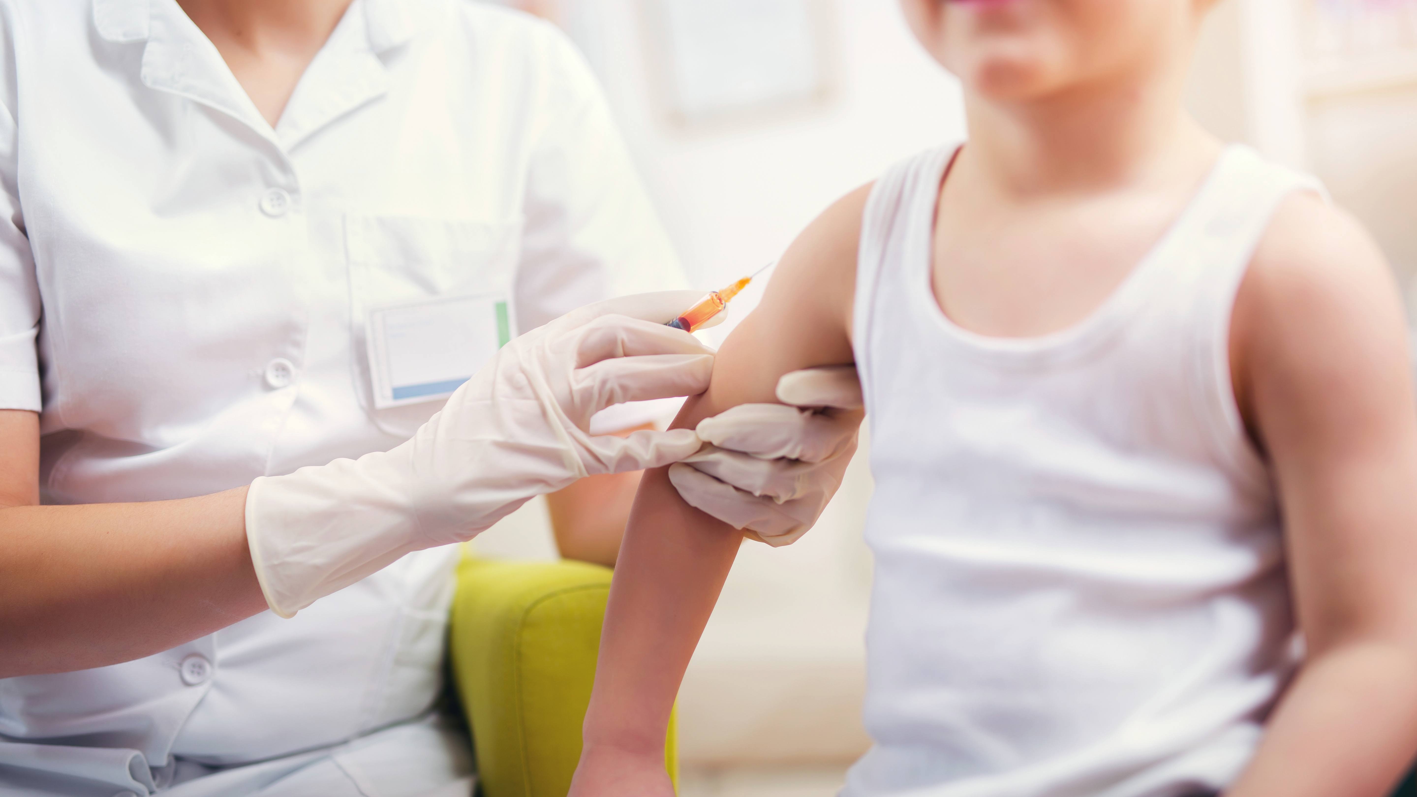 a young child in a t-shirt getting a vaccination, flu shot