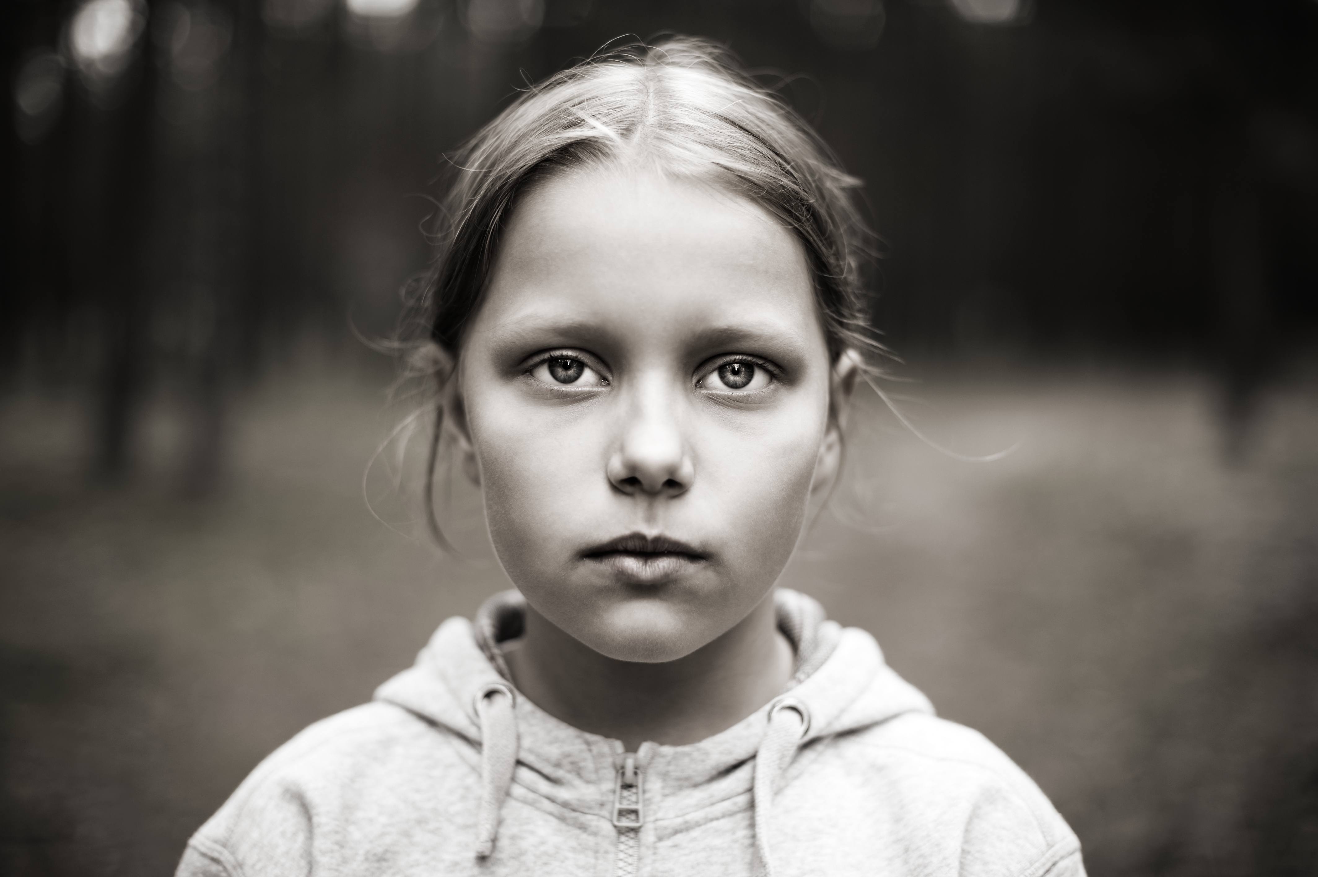a young serious, frightened and sad looking girl in a black and white photo