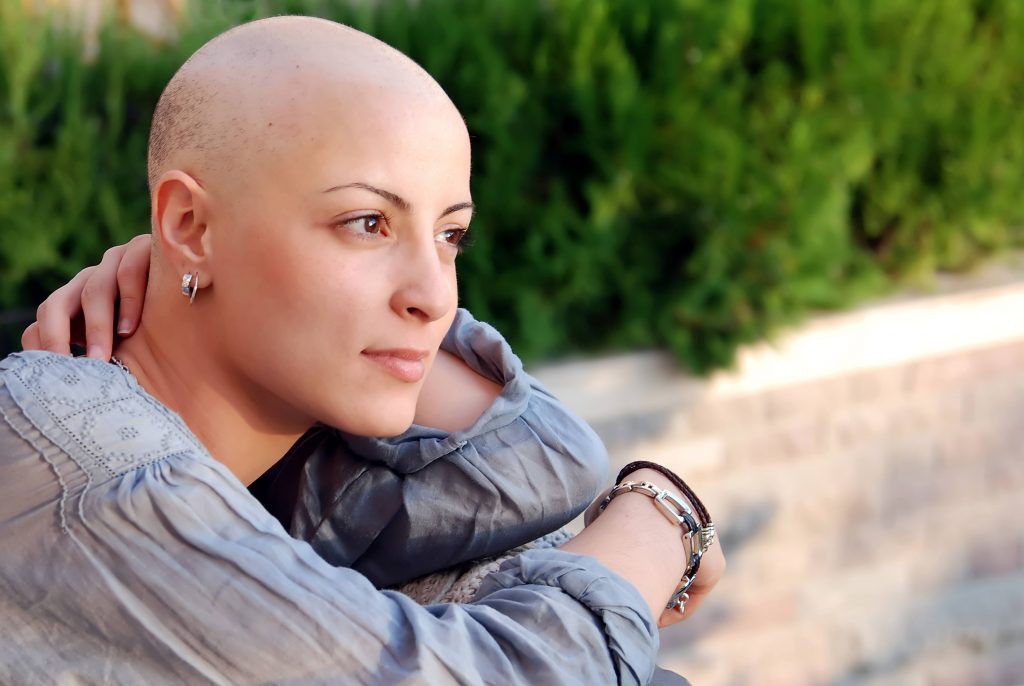 a close-up of a young woman who has lost her hair due to cancer treatment