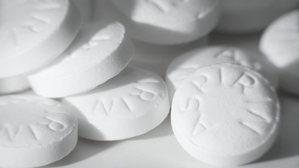 Varias tabletas de aspirina regadas sobre una superficie blanca