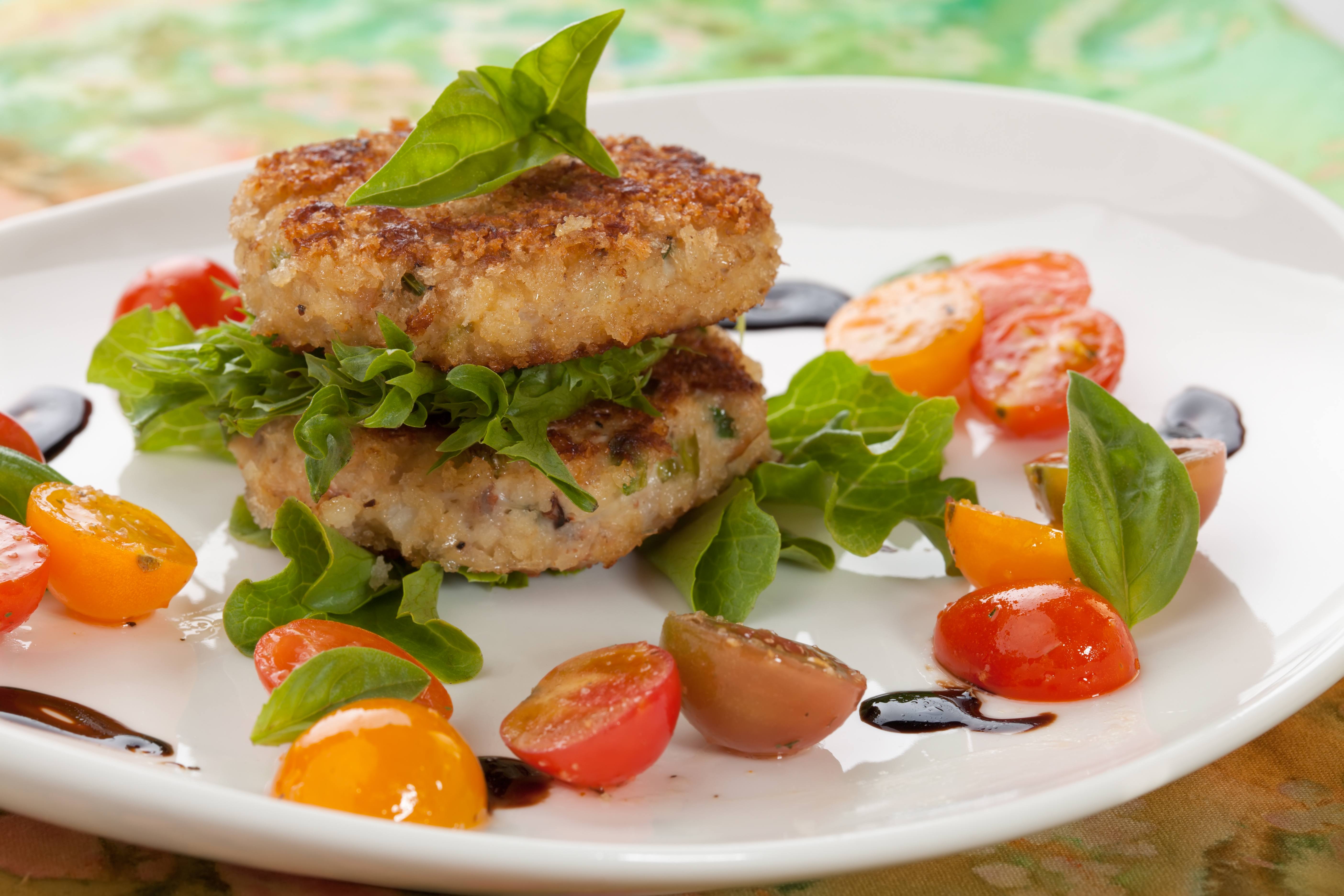 a plate with lettuce, tomatoes and crabcakes