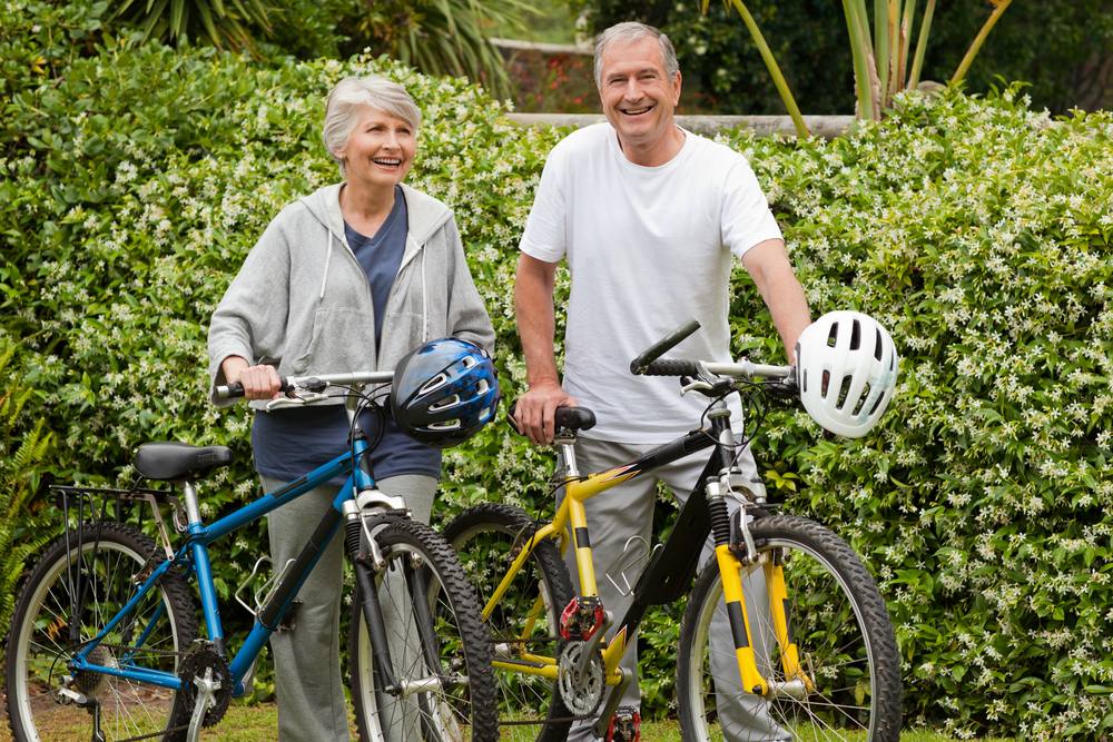 a happy looking senior couple walking with their bicycles