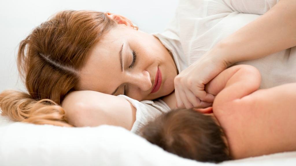 a baby breastfeeding, nursing at woman's breast