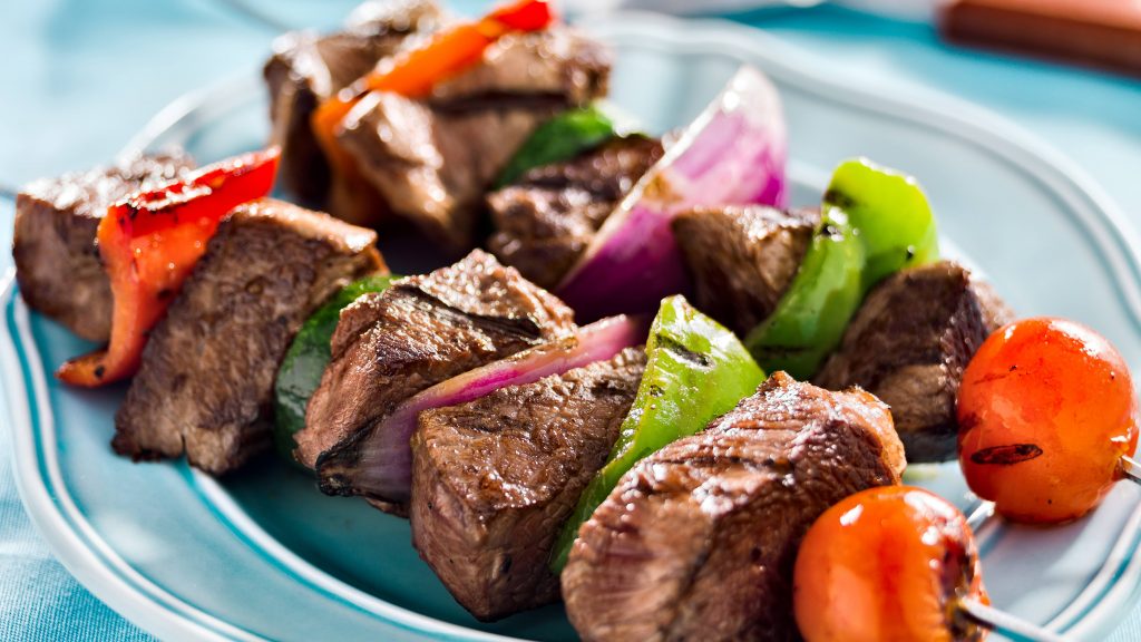a close-up of a plate of grilled beef and vegetable shish kebabs