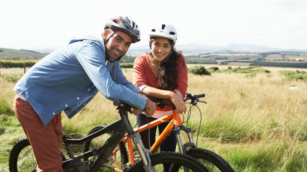 Una pareja joven anda en bicicleta por el campo