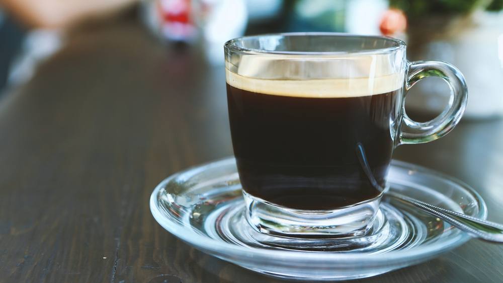 a clear glass coffee cup sitting on a counter filled with coffee