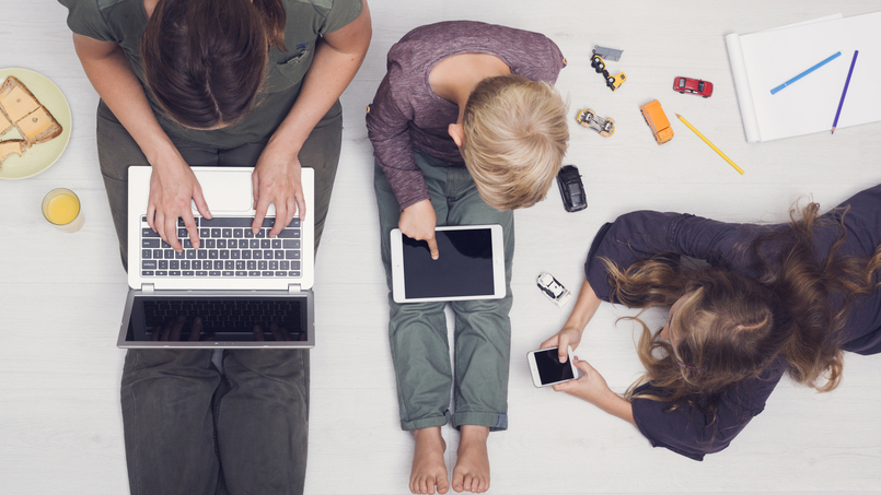 young people, perhaps students sitting on a floor with multiple digital devices, laptop computer, iPads, phones representing media addiction