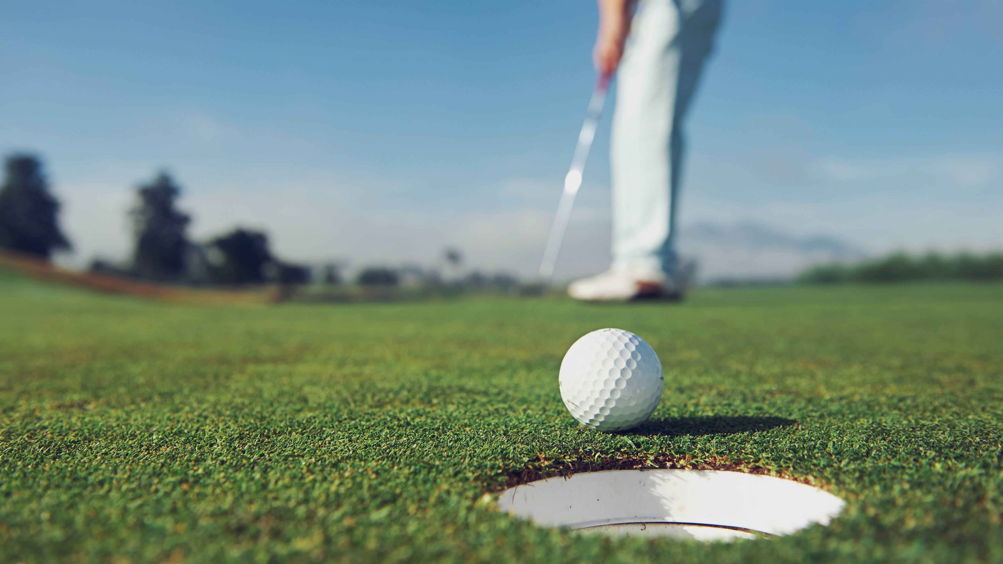 close up of a man hitting a golf ball, putting it in the hole