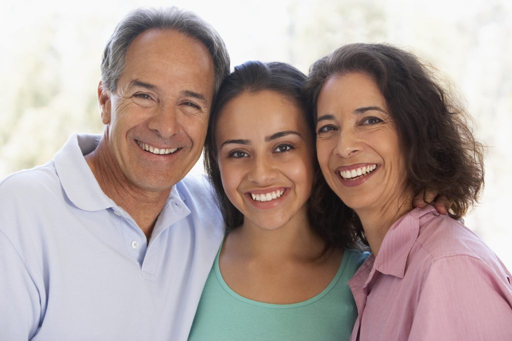 a close-up of a middle-aged couple and their daughter, all smiling