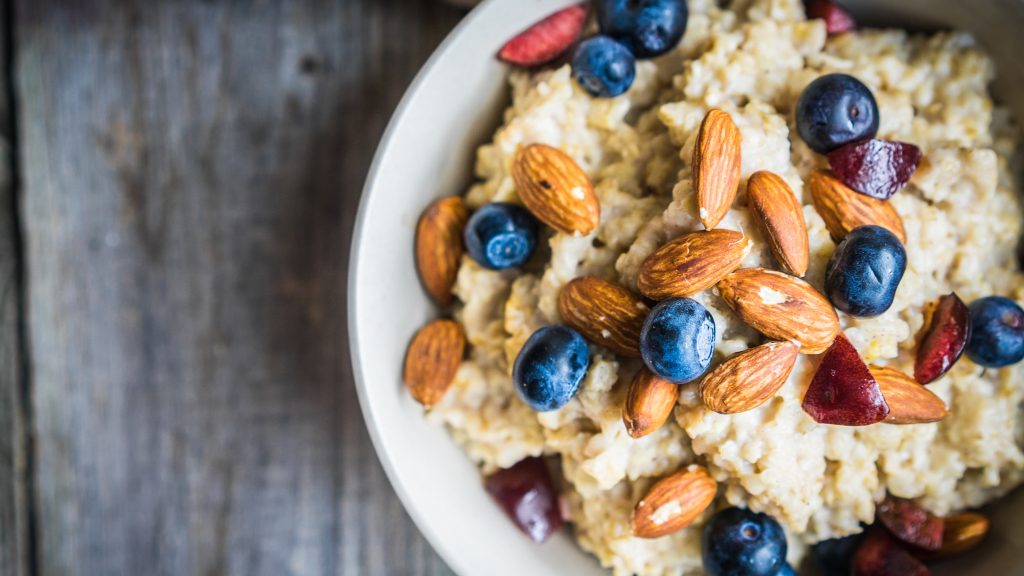 a close-up overhead view of a bowl of oatmeal with almonds, blueberries and cranberries sprinkled on top