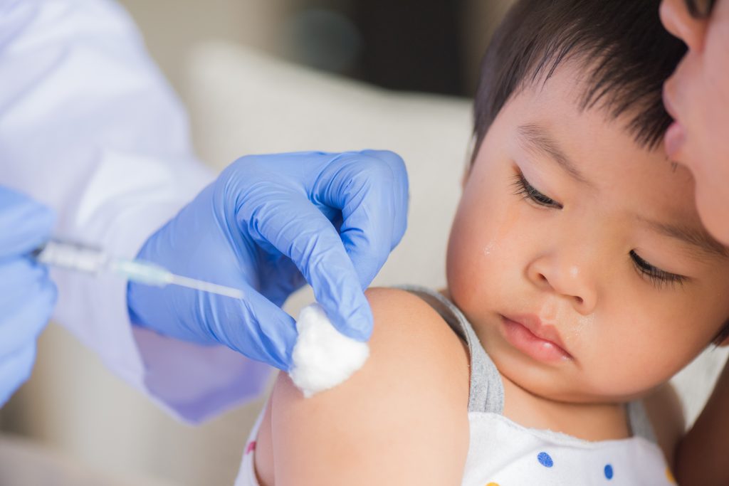 a small child being prepared to get a vaccine shot