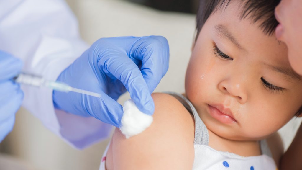 a small child being prepared to get a vaccine shot