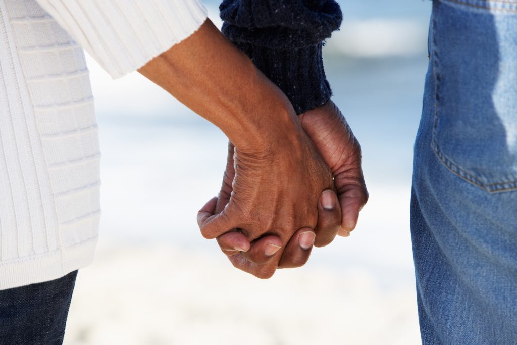 closeup of couple holding hands on the beach