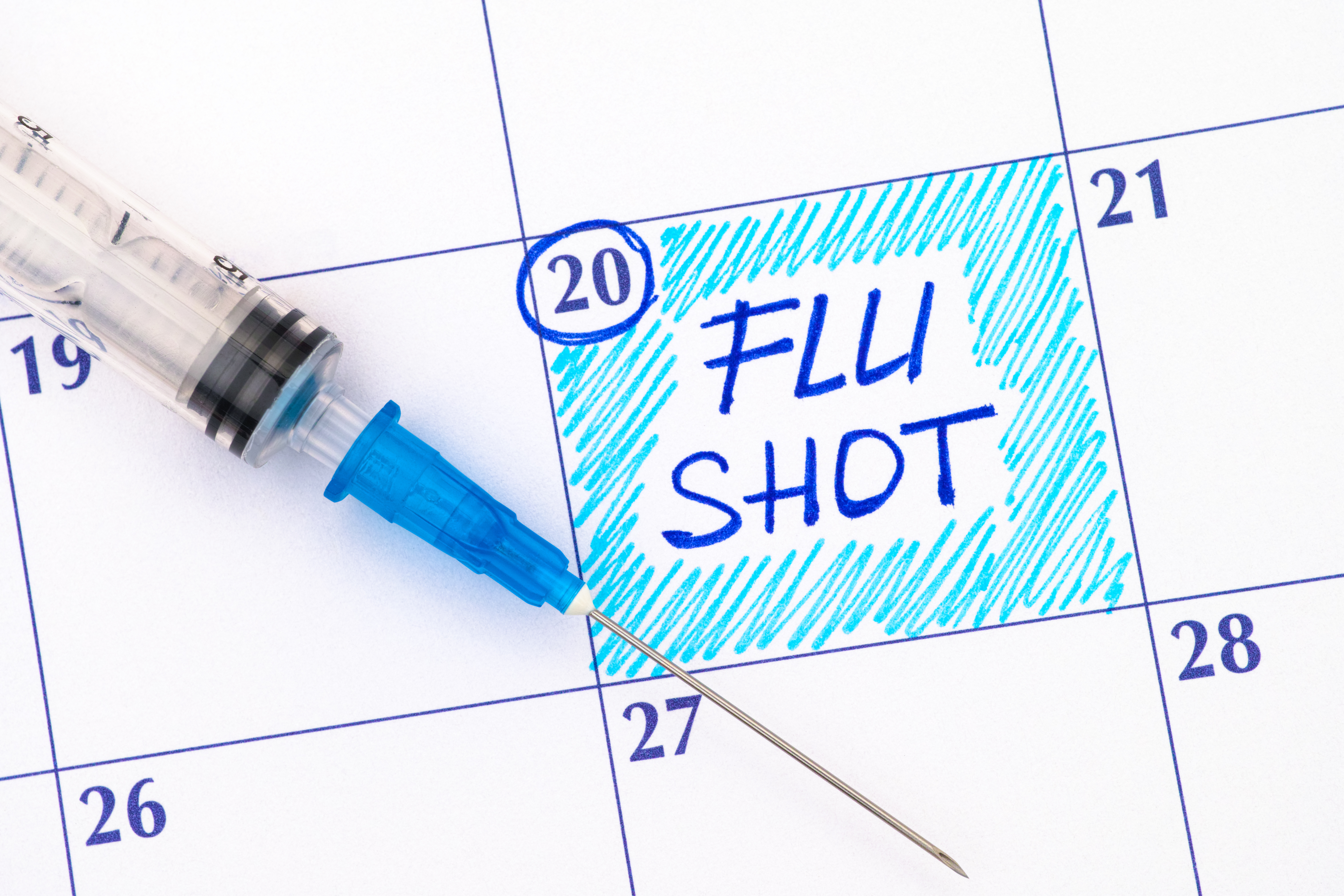 a calendar of dates with a needle on the paper and a flu shot reminder written on the page