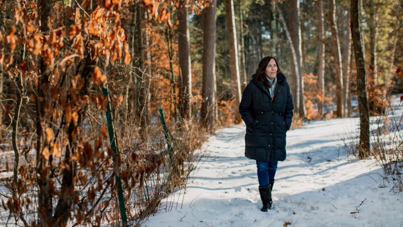 multiple myeloma patient Stacy Erholtz walking on a snow-covered path in the woods