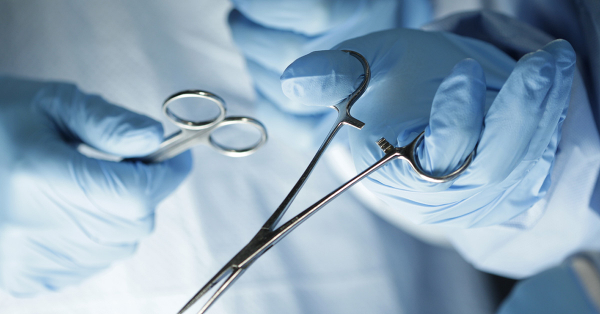 closeup of a surgeon's hands with gloves, holding surgical instruments