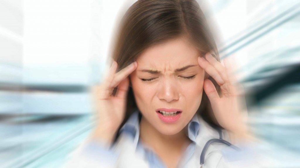 a young woman with her hands to her head in extreme pain from a headache or migraine