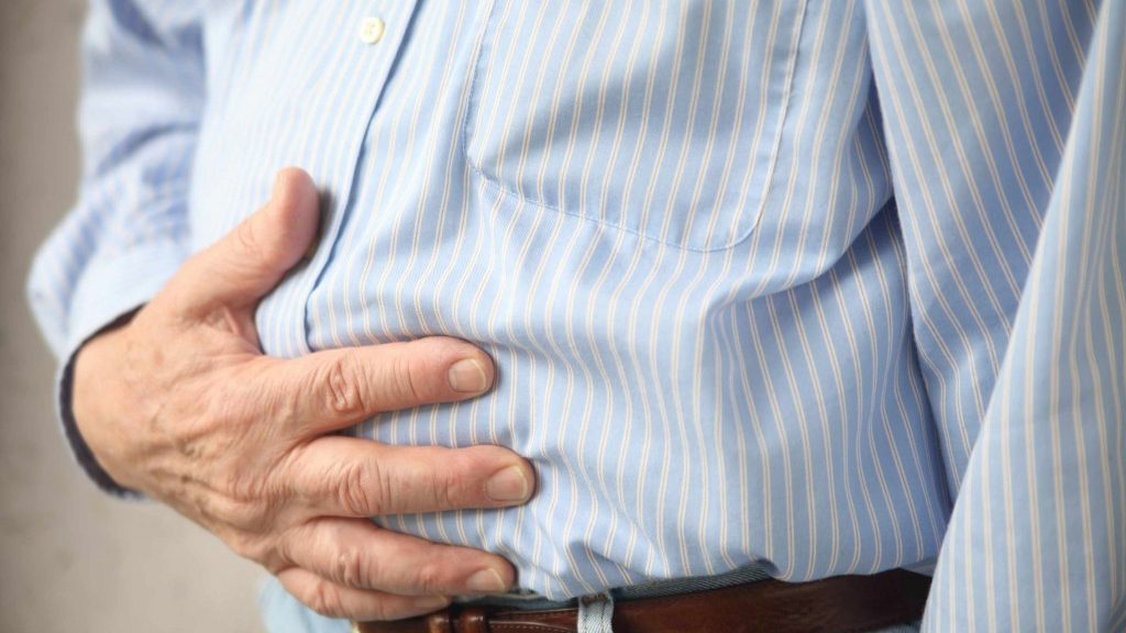a man holding his stomach as if in pain with a stomach ache, intestinal problems