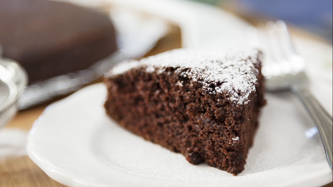 a slice of soft chocolate cake with powdered sugar sitting on a plate