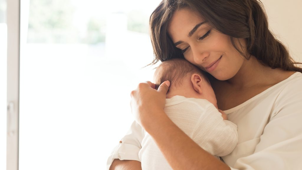 Mujer joven sosteniendo a un bebé recién nacido en sus brazos