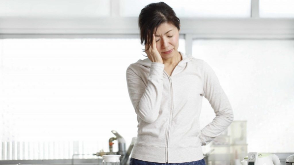 Una mujer agacha la cabeza y se frota la frente por estrés, dolor de cabeza, migraña o cansancio