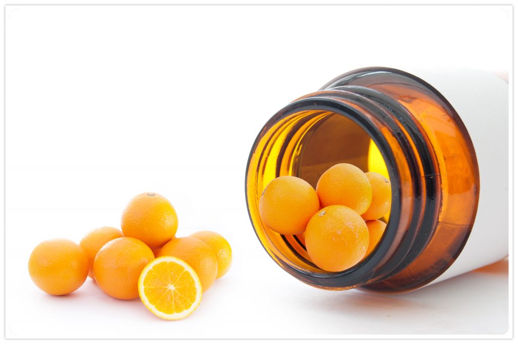 an open pill bottle on its side, spilling out oranges - vitamin C concept