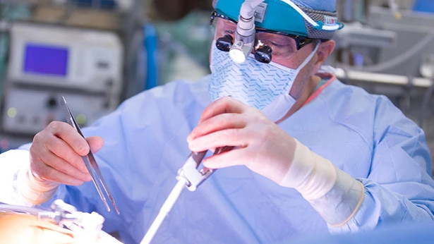 surgeon performs minimally invasive heart surgery using long instruments inserted through small incisions in the chest.